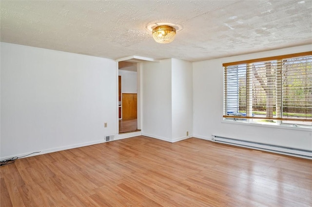 empty room featuring visible vents, a textured ceiling, light wood finished floors, and a baseboard heating unit