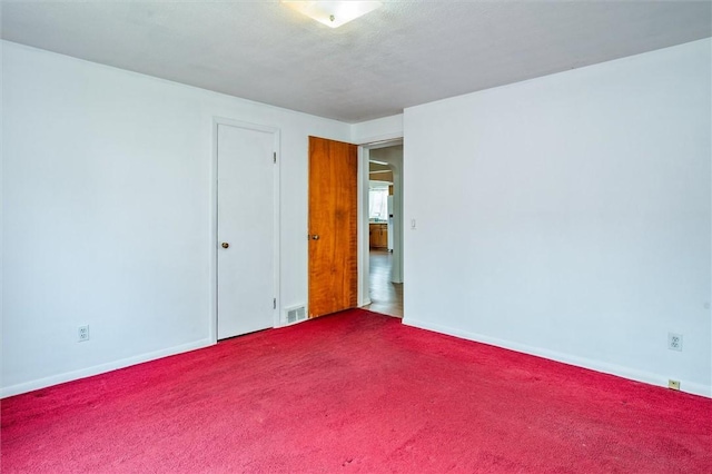 spare room with carpet floors, baseboards, and visible vents