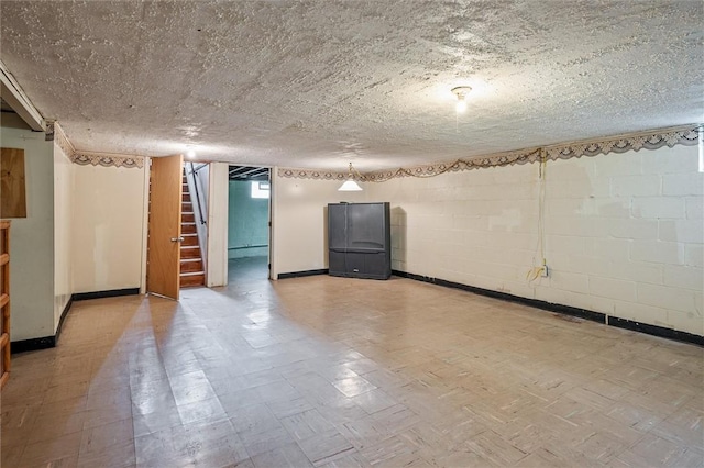 basement with stairs, concrete block wall, and baseboards