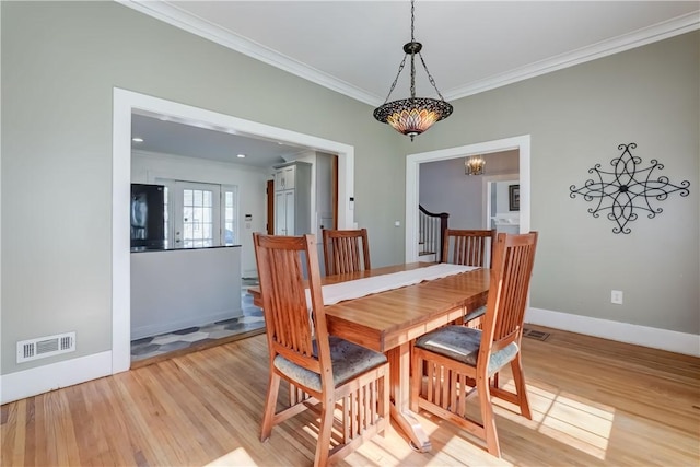 dining area featuring visible vents, ornamental molding, an inviting chandelier, baseboards, and light wood-style flooring