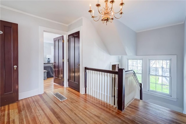 additional living space with baseboards, an inviting chandelier, wood finished floors, and visible vents