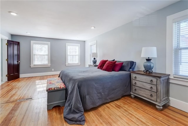 bedroom with baseboards, light wood-style flooring, and multiple windows