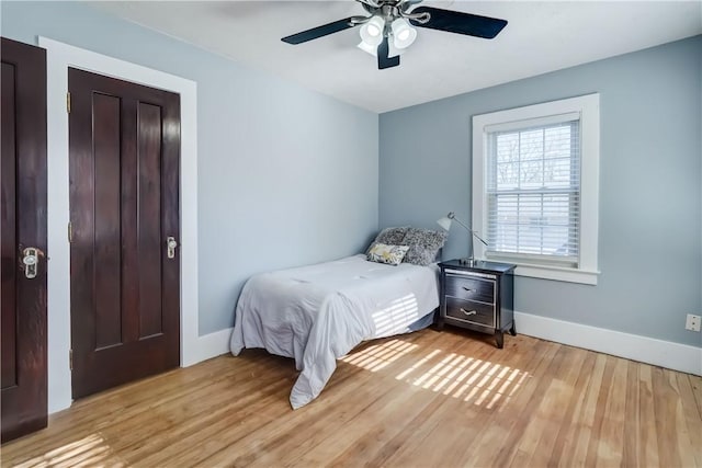 bedroom with baseboards, light wood finished floors, and ceiling fan