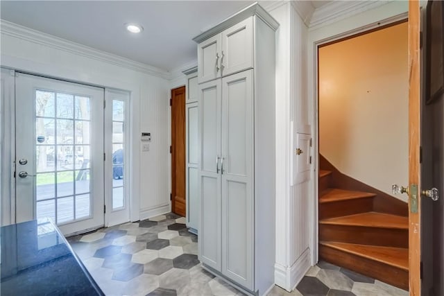 entryway with crown molding, light floors, and stairs