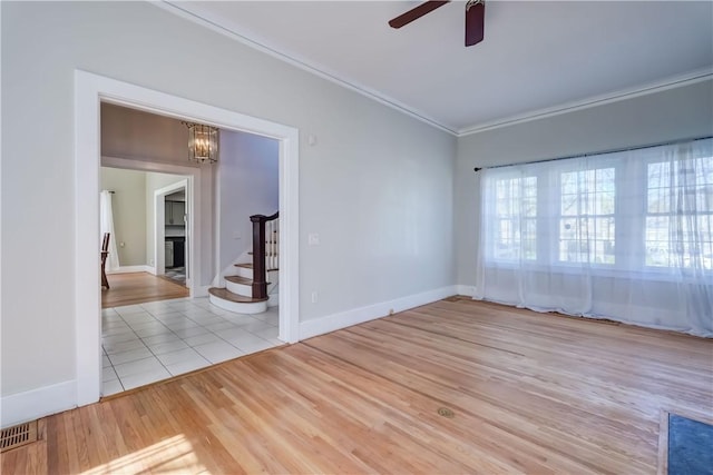 empty room with stairs, baseboards, ornamental molding, and ceiling fan with notable chandelier