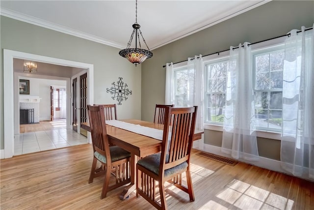 dining room with visible vents, ornamental molding, light wood-style floors, and baseboards