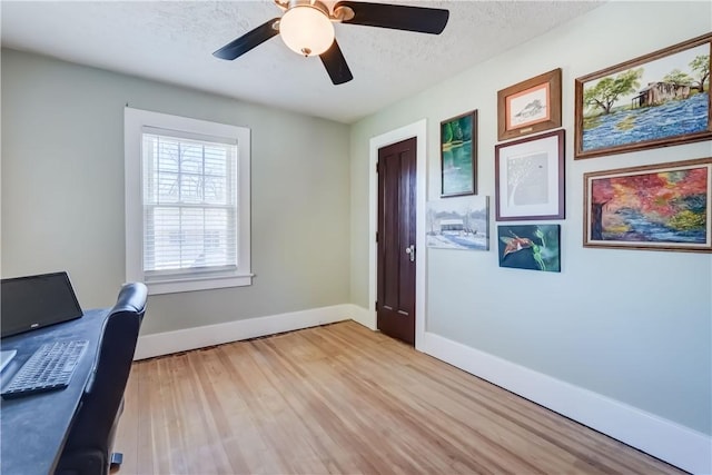 home office featuring baseboards, a textured ceiling, light wood finished floors, and a ceiling fan