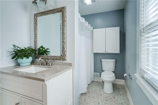 bathroom featuring toilet, baseboards, visible vents, and a wealth of natural light