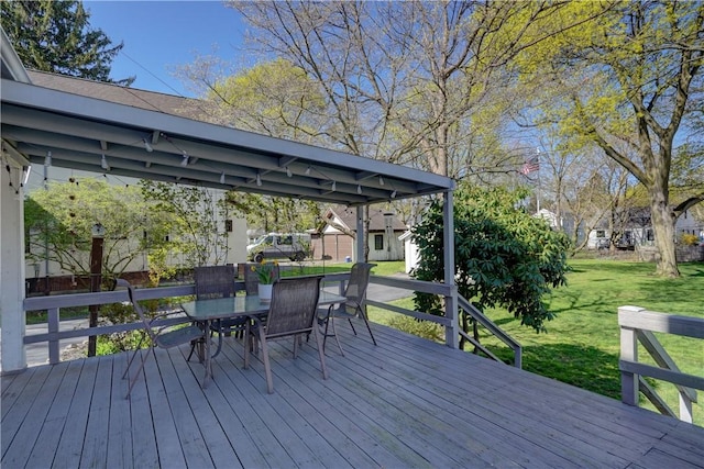 wooden deck featuring a lawn, outdoor dining area, and an outbuilding