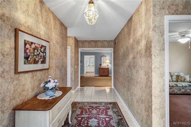 hallway with baseboards, an inviting chandelier, and tile patterned flooring