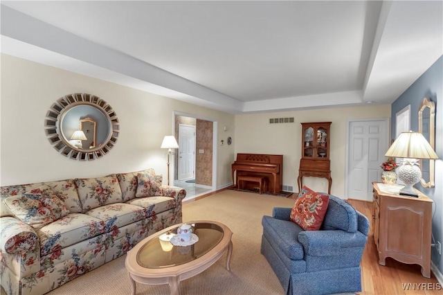living room featuring a tray ceiling and visible vents