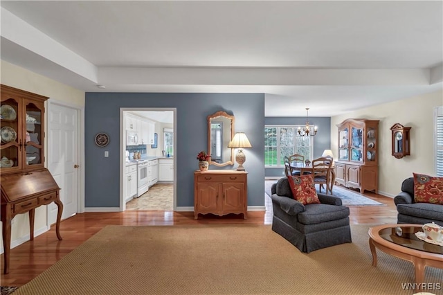 living room featuring an inviting chandelier, light wood-style floors, and baseboards