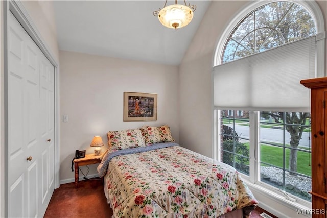 bedroom featuring a closet, baseboards, vaulted ceiling, and dark carpet