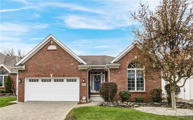 ranch-style home featuring brick siding, decorative driveway, roof with shingles, and a garage