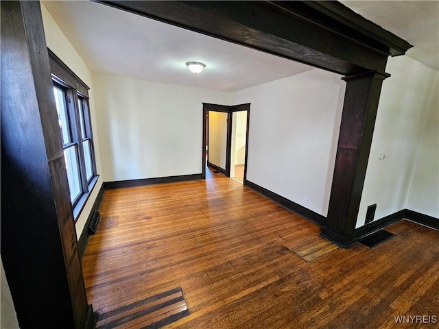 spare room featuring baseboards, wood finished floors, and visible vents
