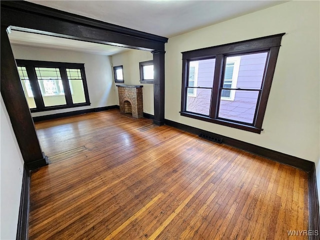 unfurnished living room featuring wood-type flooring, baseboards, and a fireplace