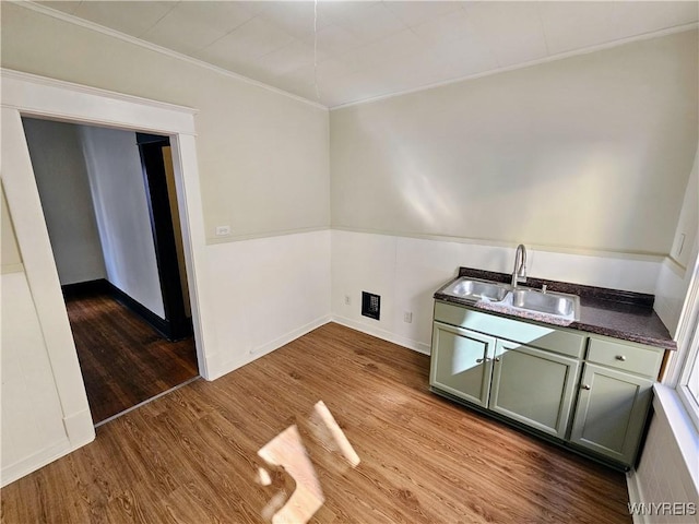 clothes washing area with crown molding, baseboards, a sink, and wood finished floors