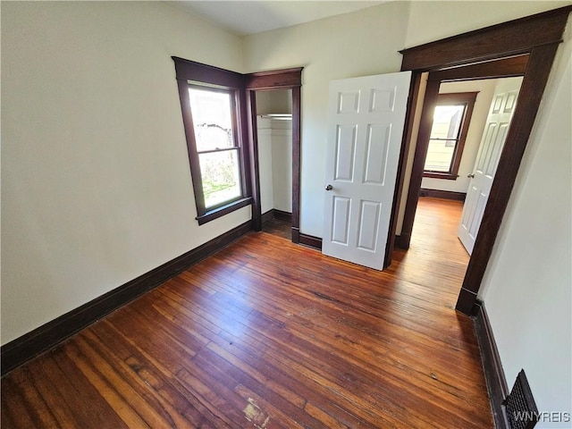 unfurnished bedroom featuring baseboards, dark wood finished floors, and a closet