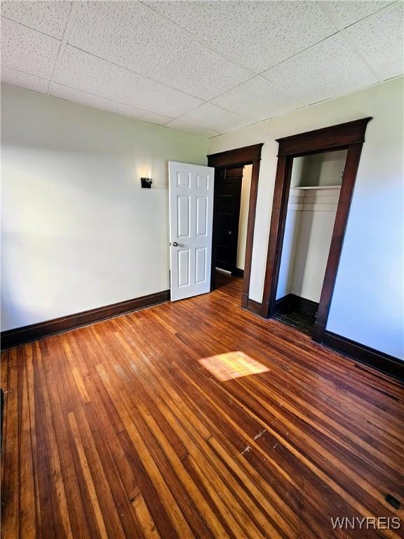 unfurnished bedroom featuring multiple closets, baseboards, and hardwood / wood-style flooring