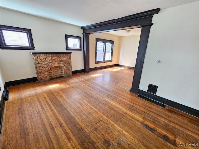 unfurnished living room with baseboards, hardwood / wood-style floors, and visible vents