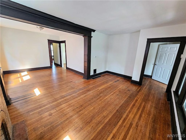 empty room featuring baseboards, wood finished floors, and visible vents