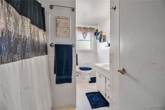 full bathroom featuring wainscoting, vanity, toilet, tile patterned floors, and tile walls