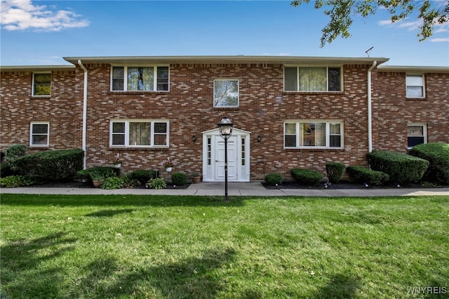 view of property featuring brick siding and a front lawn