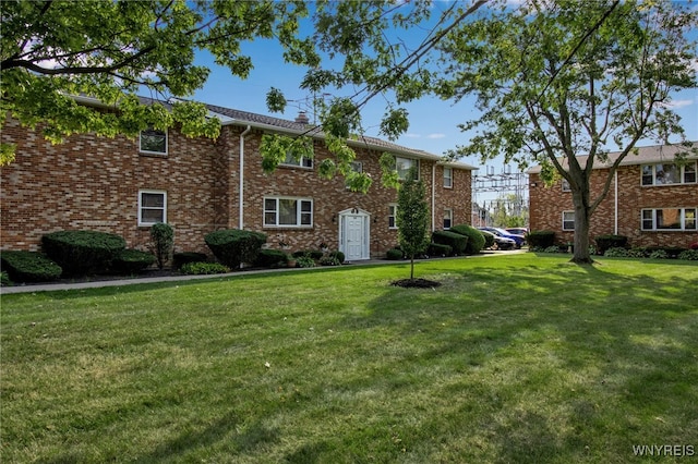 view of front of house featuring brick siding and a front yard