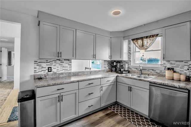 kitchen featuring wood finished floors, decorative backsplash, a sink, and dishwasher