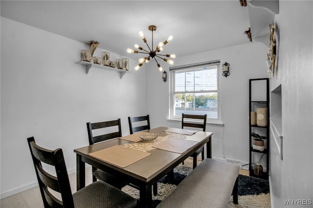 dining room featuring baseboards, light wood finished floors, and a chandelier