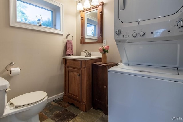 21959 County Route 59, Brownville, NY 13634 - half bathroom featuring stacked washer and dryer, vanity, toilet, baseboards, and stone tile flooring