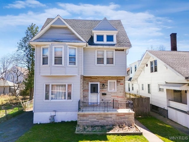 723 Pine Ave, Niagara Falls, NY 14301 - view of front facade featuring fence, a shingled roof, stone siding, and a front lawn