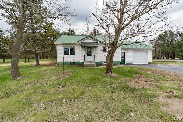 bungalow featuring aphalt driveway, metal roof, a chimney, a front lawn, and entry steps