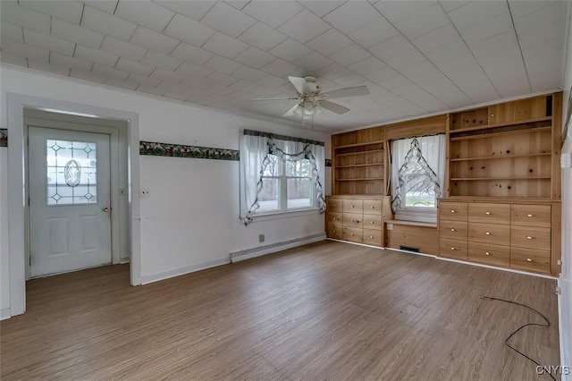 spare room with baseboard heating, built in features, a ceiling fan, baseboards, and wood finished floors
