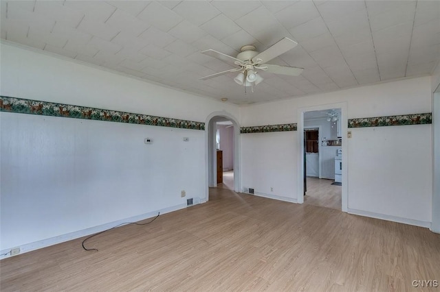 spare room featuring arched walkways, ceiling fan, light wood-style flooring, and visible vents