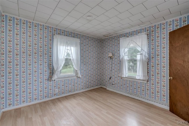 unfurnished room featuring wood finished floors and wallpapered walls