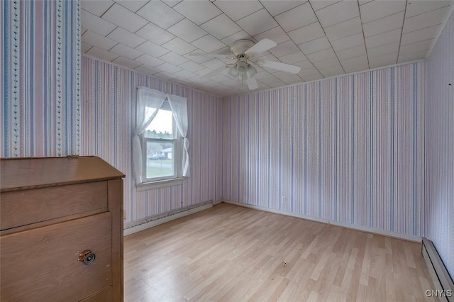 unfurnished room featuring wood finished floors, a baseboard heating unit, and wallpapered walls