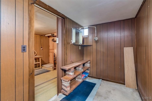 interior space featuring wooden walls and unfinished concrete floors