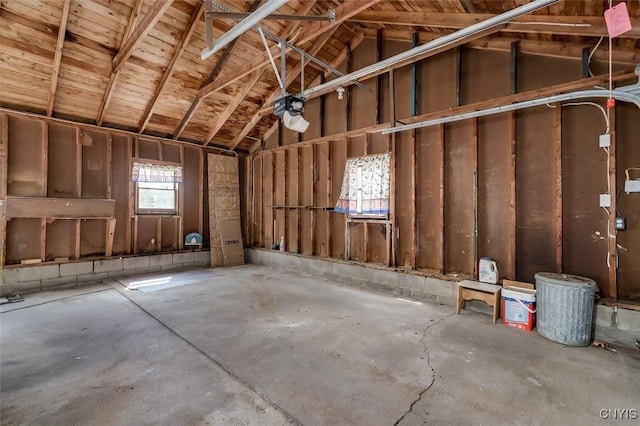 misc room featuring a garage, lofted ceiling, and unfinished concrete floors