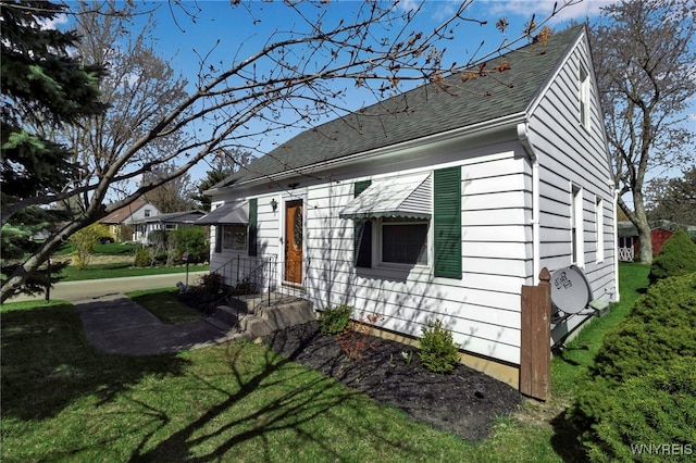 view of front facade featuring roof with shingles and a front yard