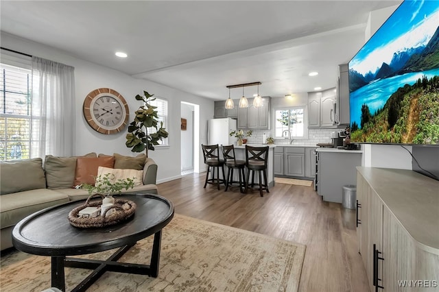 living area featuring recessed lighting, light wood-style flooring, and baseboards