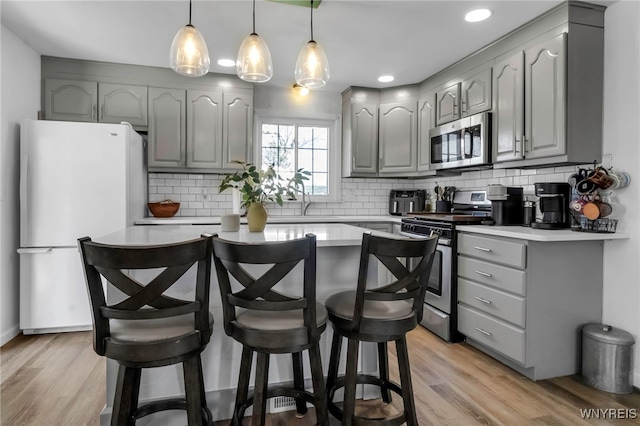 kitchen with gray cabinetry, light countertops, a center island, and stainless steel appliances