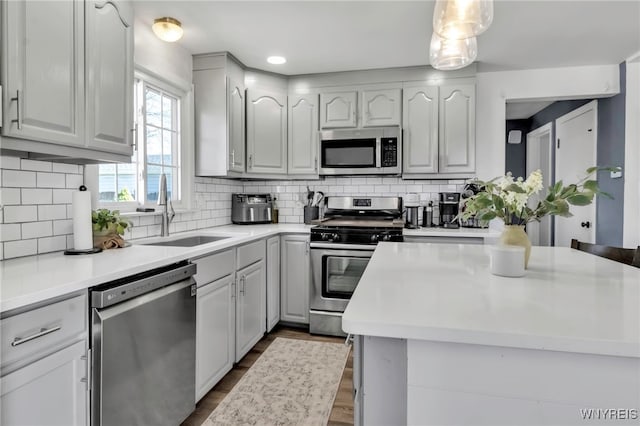 kitchen featuring light countertops, appliances with stainless steel finishes, a sink, and dark wood-type flooring