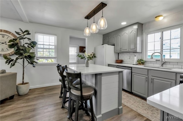 kitchen with a sink, gray cabinets, freestanding refrigerator, backsplash, and stainless steel dishwasher