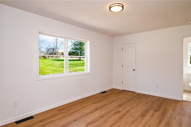 spare room with baseboards, light wood finished floors, and visible vents