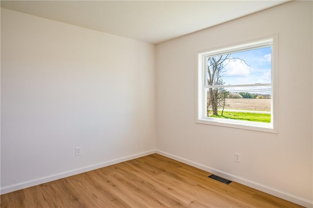 unfurnished room featuring baseboards, visible vents, and light wood-type flooring