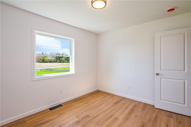 unfurnished room with baseboards, light wood-type flooring, and visible vents