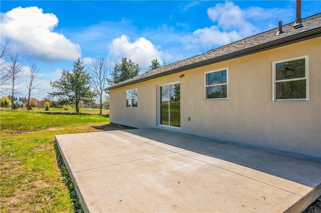 rear view of property with a patio, stucco siding, and a yard