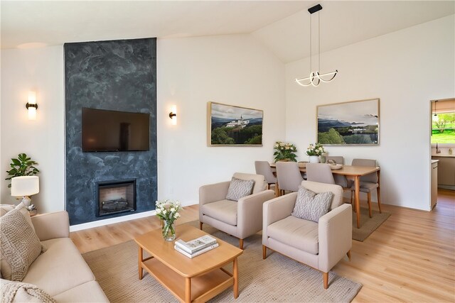 living room with a fireplace, vaulted ceiling, and light wood-type flooring