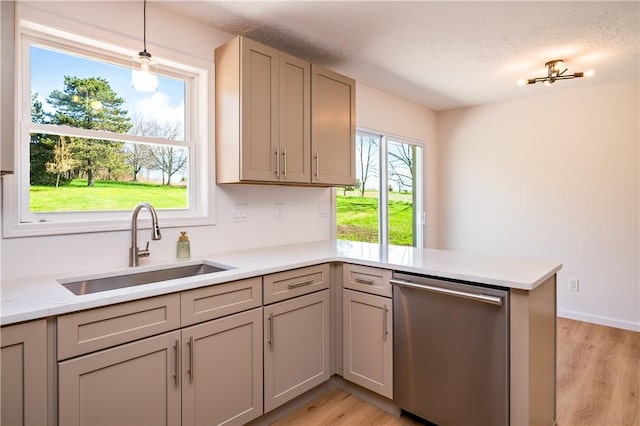 kitchen featuring stainless steel dishwasher, a sink, gray cabinetry, light wood finished floors, and a peninsula